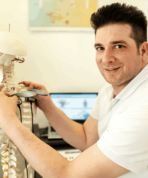 Chiropraktiker Metin Kenan Sisik demonstriert in seiner Praxis in Ulm chiropraktische Zusammenhänge an einem Skelettmodell zur Patientenaufklärung.